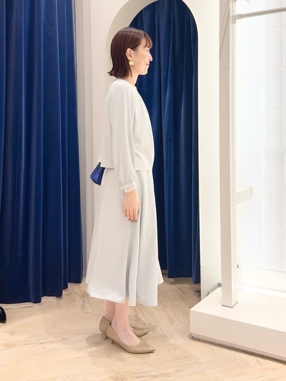 ブルー系のスカート、ブルー系のシャツ/ブラウス、ホワイト系のショルダーバッグを着用したレディースの秋コーディネートの4枚目の写真