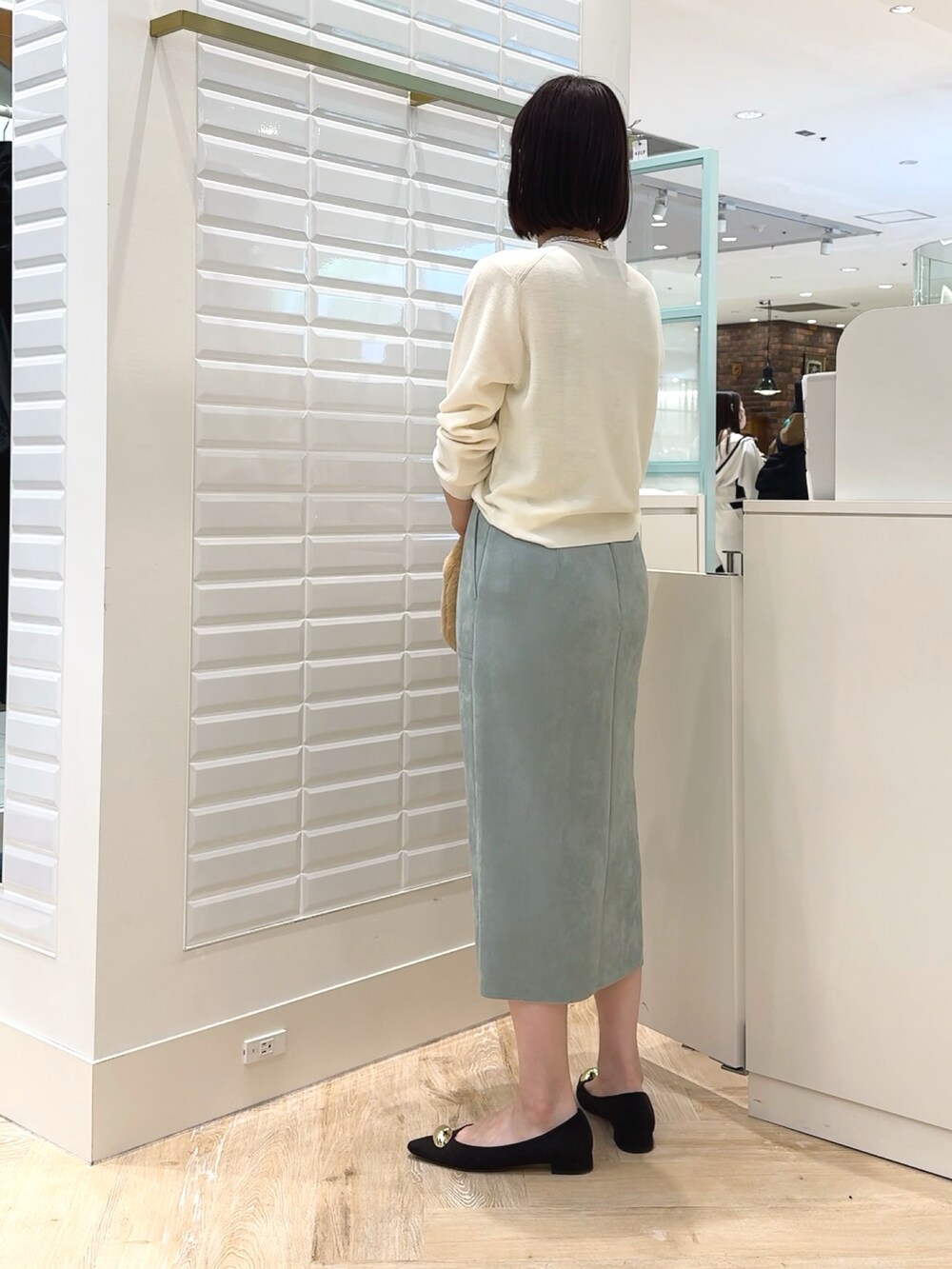 ホワイト系のカーディガン/ボレロ、ベージュ系のショルダーバッグ、グリーン系のスカートを着用したレディースの秋コーディネートの4枚目の写真