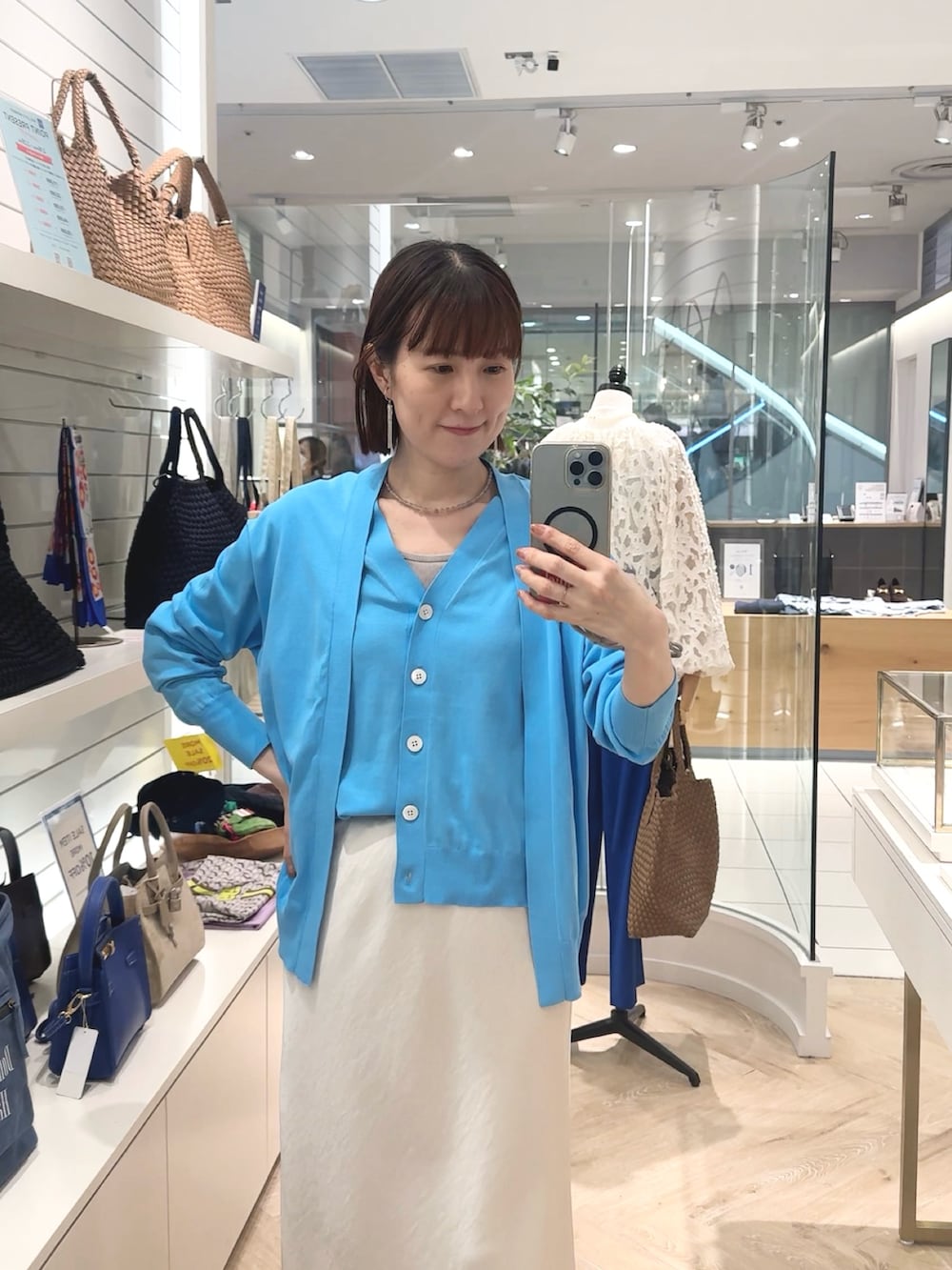 ホワイト系のスカート、ブルー系のカーディガン/ボレロ、グレー系のネックレスを着用したレディースの春コーディネートの2枚目の写真