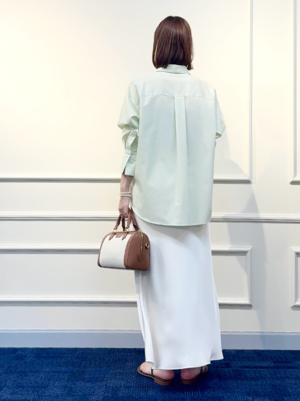 ブラウン系のボストンバッグ、ホワイト系のスカート、グリーン系のシャツ/ブラウスを着用したレディースの冬コーディネートの9枚目の写真