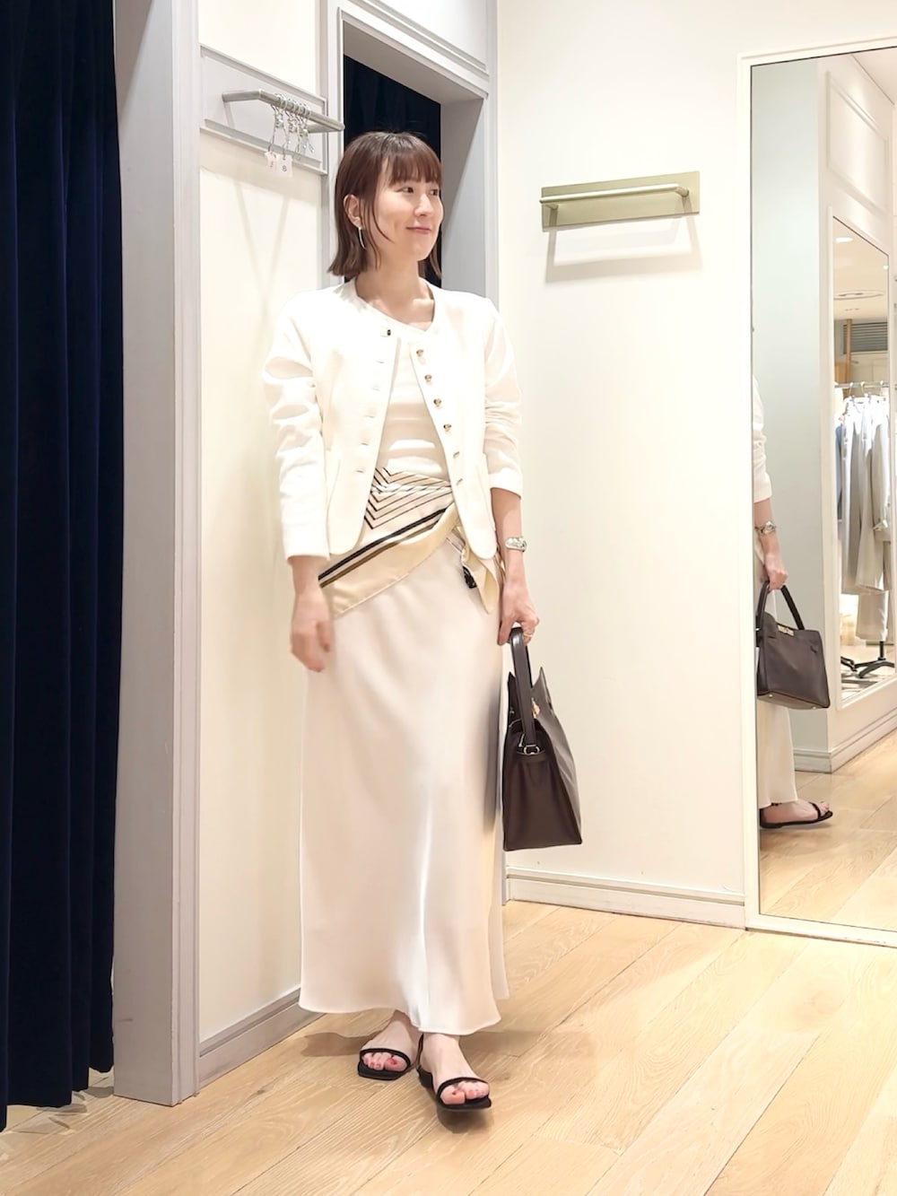 ホワイト系のタンクトップ、ホワイト系のノーカラージャケット、ホワイト系のスカートを着用したレディースの春コーディネートの2枚目の写真