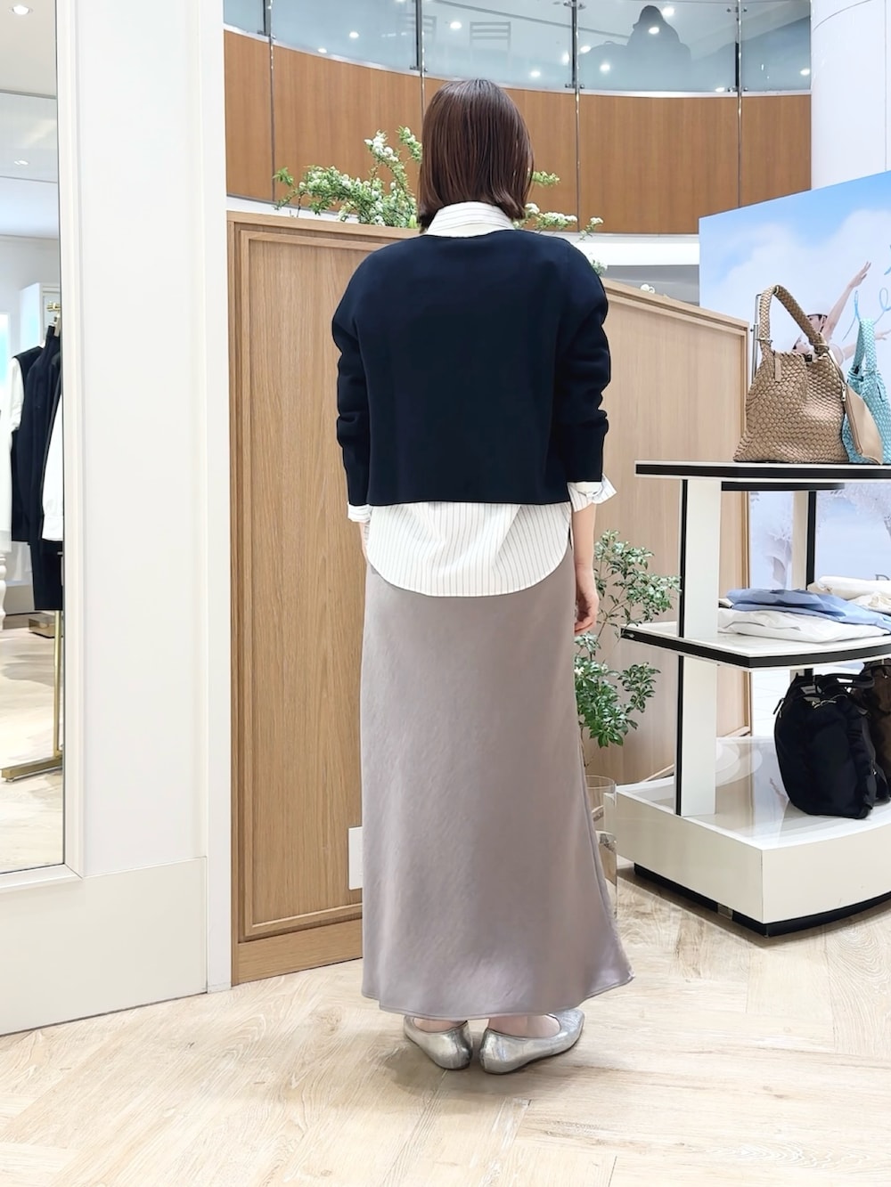 グリーン系のスカート、ベージュ系のトートバッグ、ブルー系のカーディガン/ボレロを着用したレディースの春コーディネートの3枚目の写真