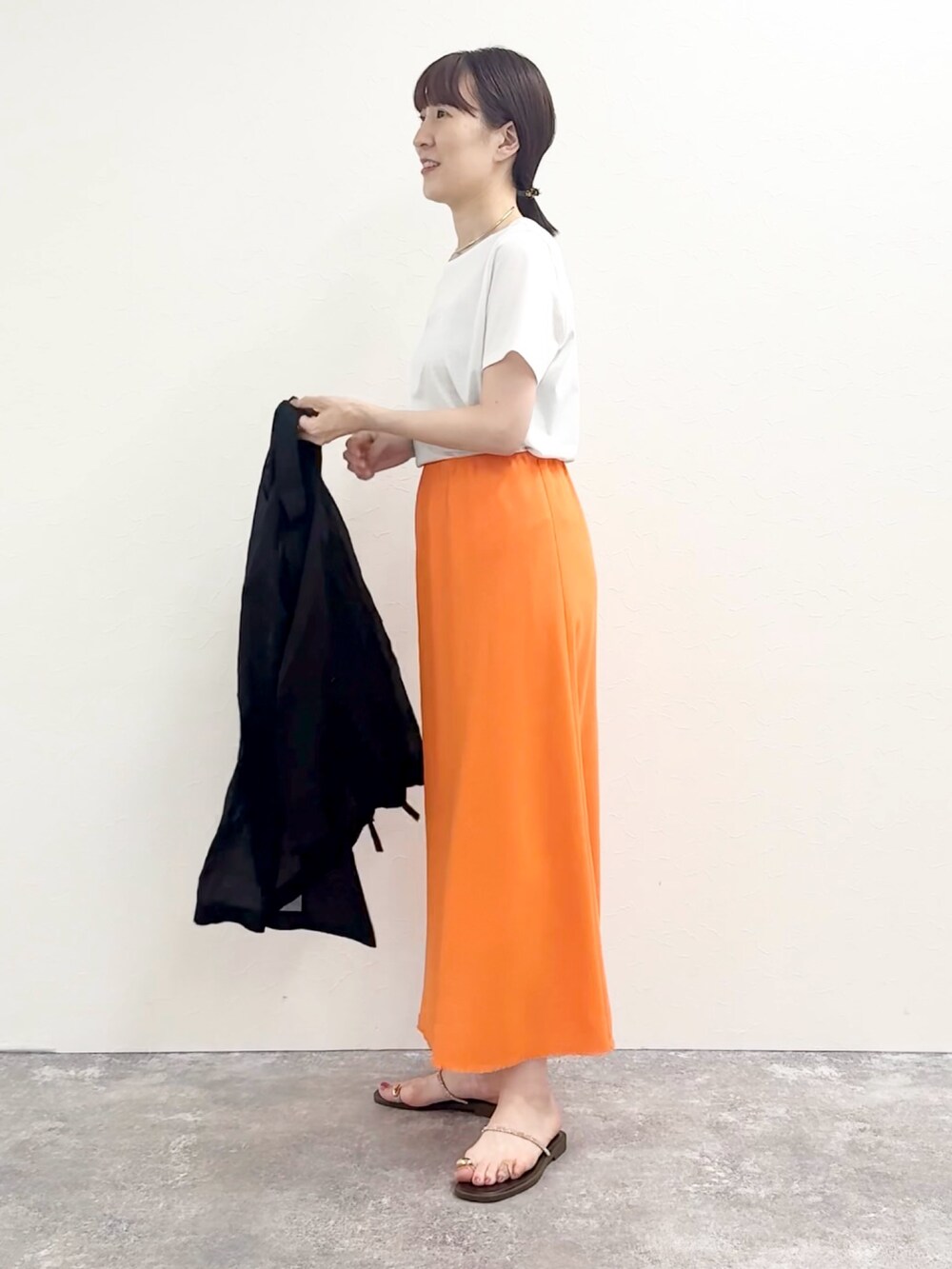 ホワイト系のTシャツ/カットソー、オレンジ系のスカート、ブラウン系のサンダルを着用したレディースの夏コーディネートの6枚目の写真
