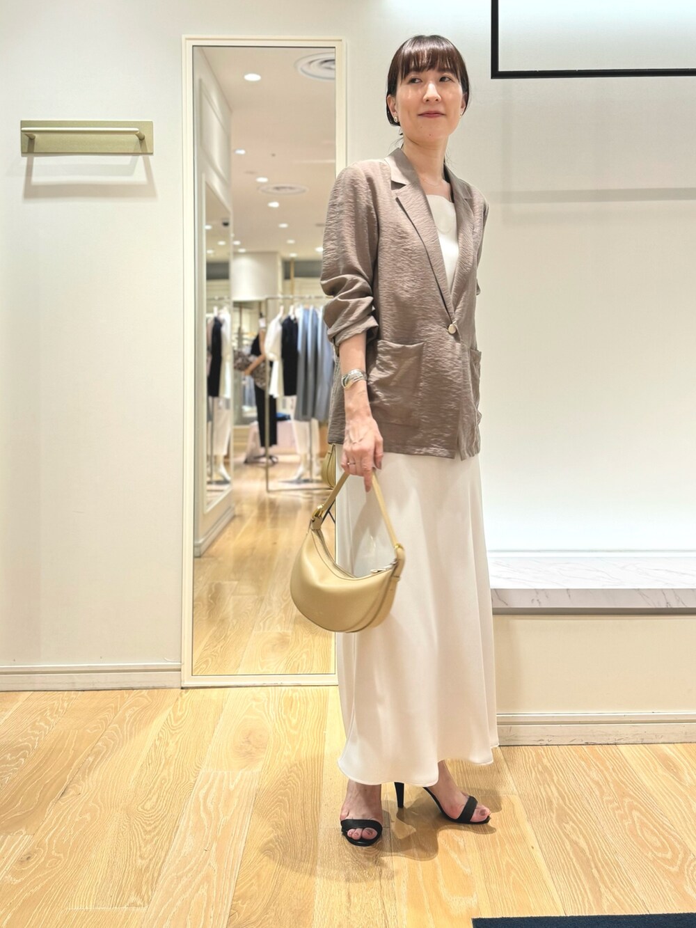 グリーン系のテーラードジャケット、ホワイト系のタンクトップ、ホワイト系のスカートを着用したレディースの夏コーディネートの7枚目の写真