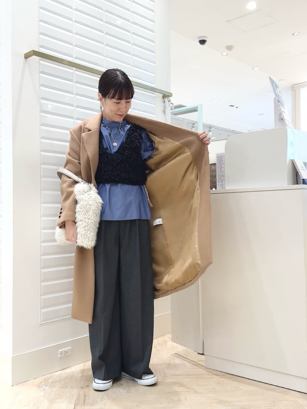 グレー系のベスト、ブルー系のシャツ/ブラウス、ホワイト系のショルダーバッグを着用したレディースの秋コーディネートの7枚目の写真