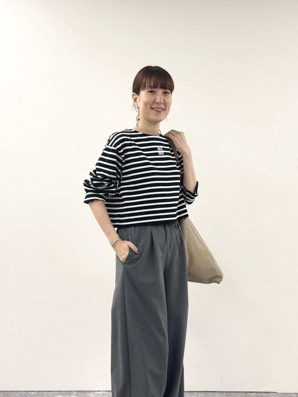 ブラック系のTシャツ/カットソー、ベージュ系のショルダーバッグ、グレー系のその他パンツを着用したレディースの秋コーディネートの5枚目の写真