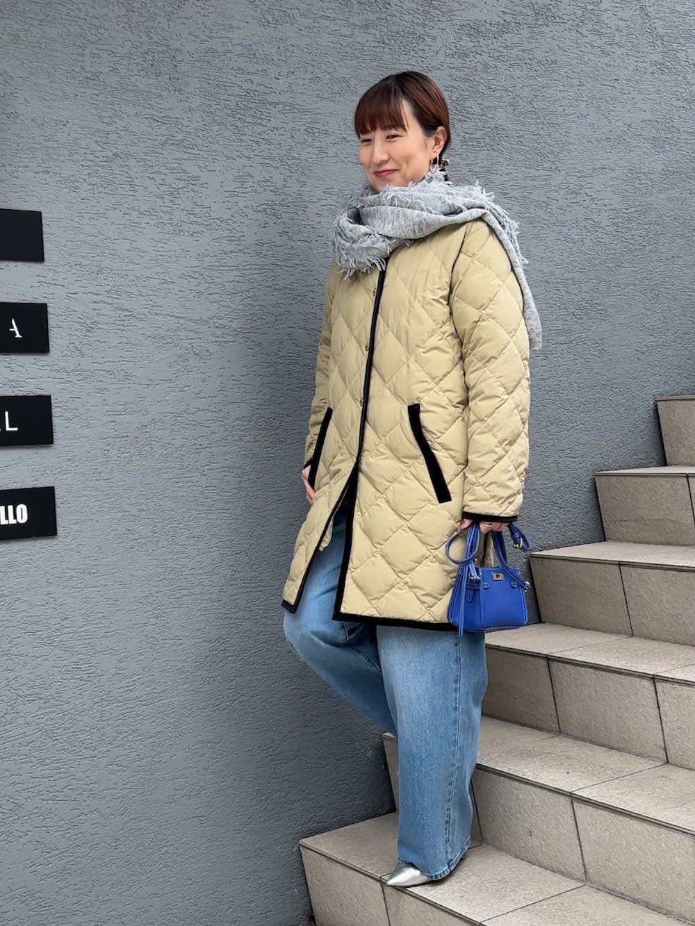 ブルー系のデニムパンツ、ブルー系のショルダーバッグ、ベージュ系のダウンジャケット/コートを着用したレディースの秋コーディネートの3枚目の写真