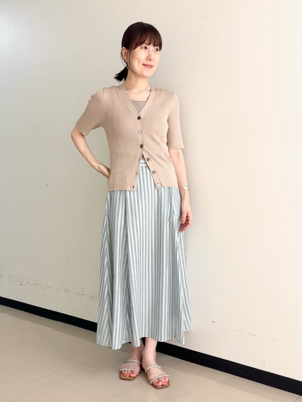 ブルー系のスカート、ベージュ系のカーディガン/ボレロ、ベージュ系のタンクトップを着用したレディースの夏コーディネートの4枚目の写真