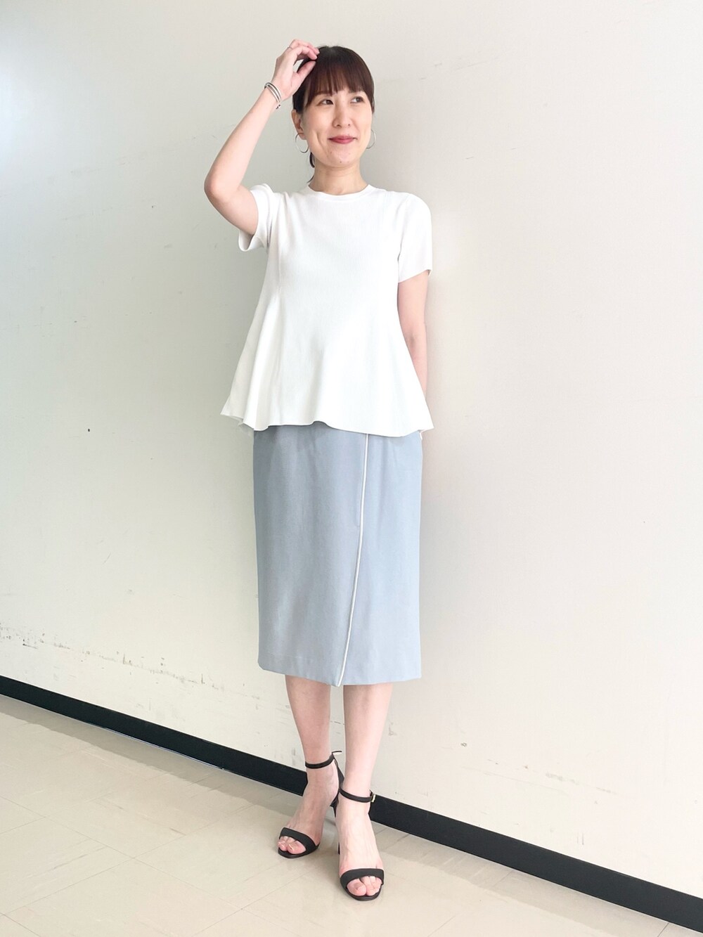 ブルー系のスカート、ホワイト系のニット/セーターを着用したレディースの春コーディネートの2枚目の写真