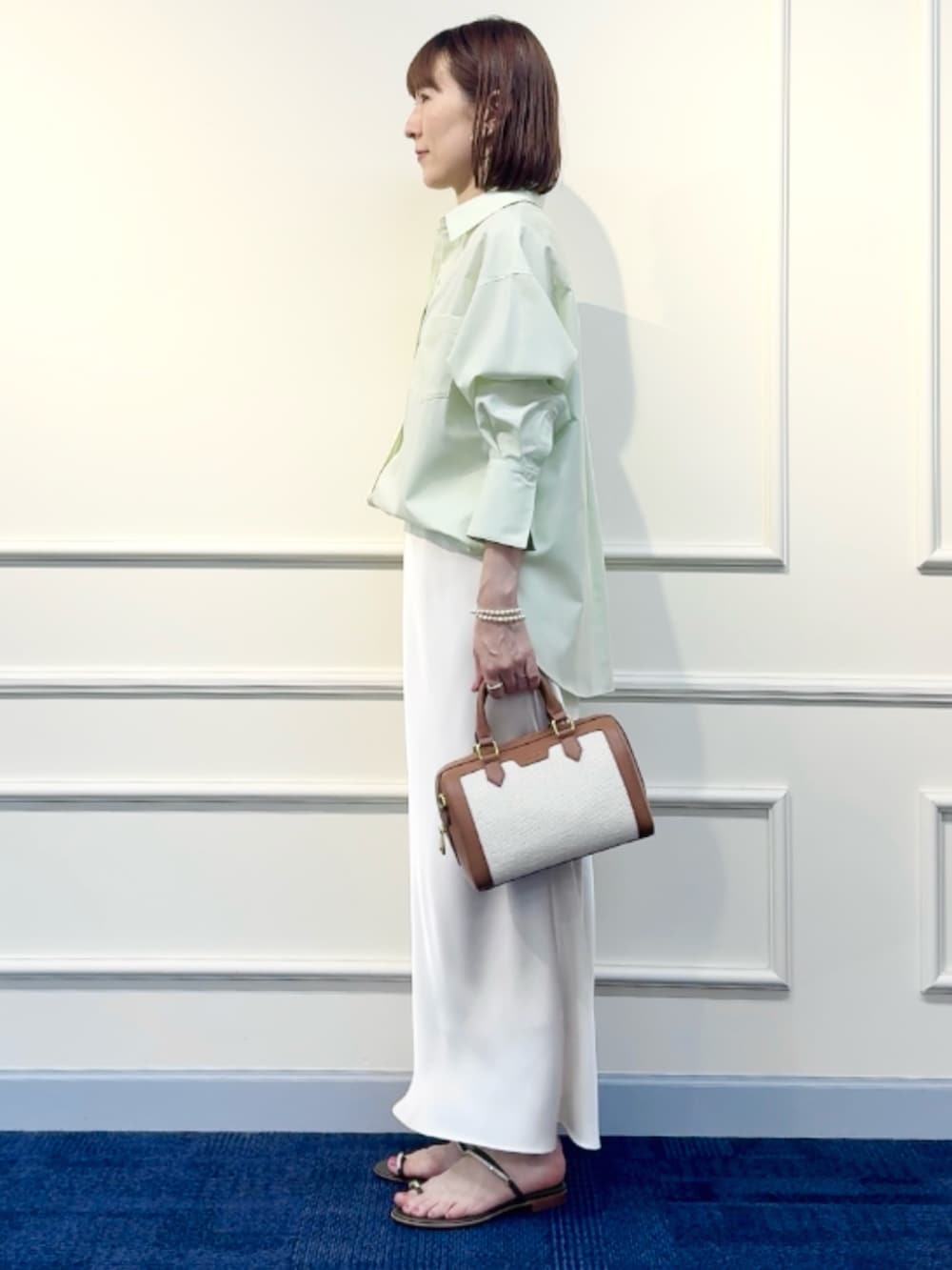 ブラウン系のボストンバッグ、ホワイト系のスカート、グリーン系のシャツ/ブラウスを着用したレディースの冬コーディネートの8枚目の写真