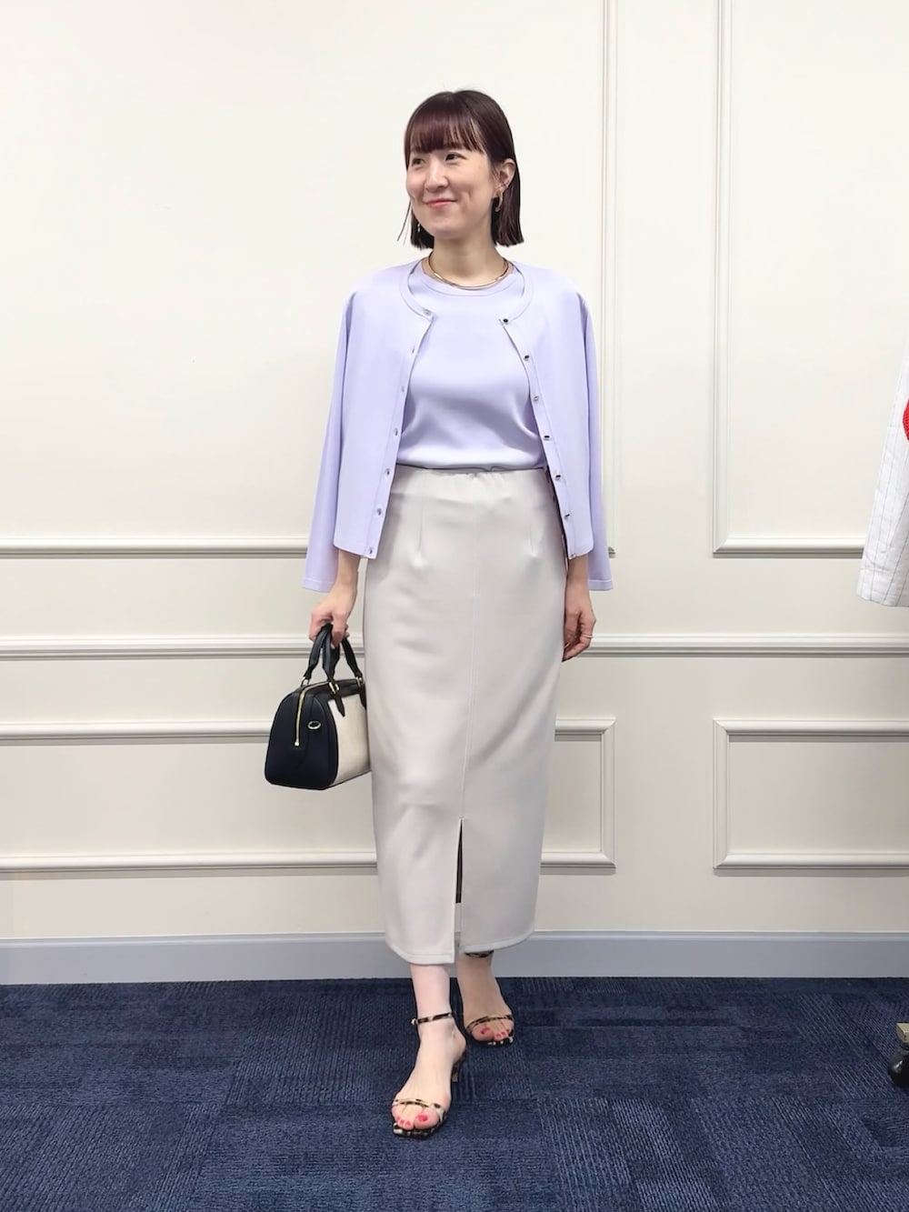 ブラック系のボストンバッグ、パープル系のカーディガン/ボレロ、パープル系のニット/セーターを着用したレディースの春コーディネートの4枚目の写真