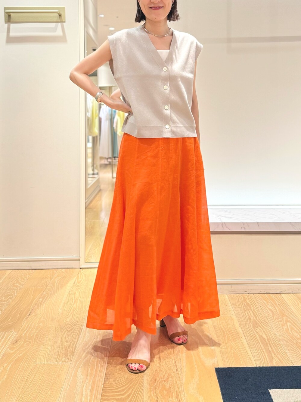 ベージュ系のベスト、ホワイト系のタンクトップ、オレンジ系のスカートを着用したレディースの夏コーディネートの10枚目の写真