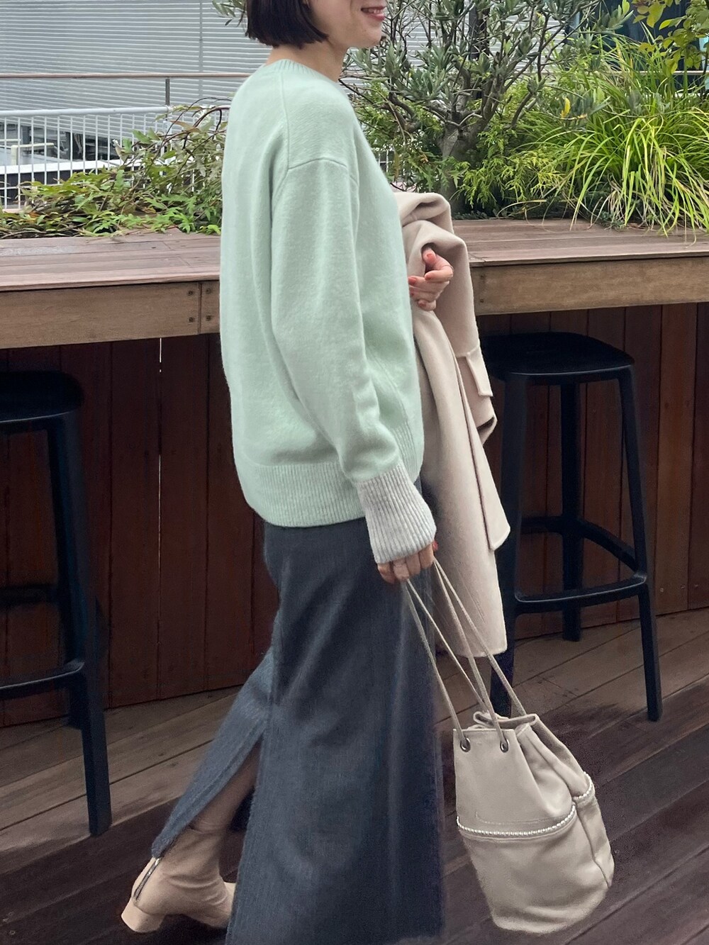 ベージュ系のトートバッグ、グレー系のスカート、グリーン系のニット/セーターを着用したレディースの冬コーディネートの4枚目の写真