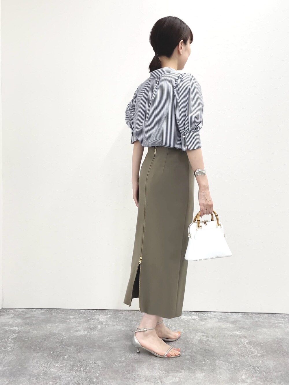 シルバー系のサンダル、グリーン系のスカート、ホワイト系のショルダーバッグを着用したレディースの春コーディネートの9枚目の写真