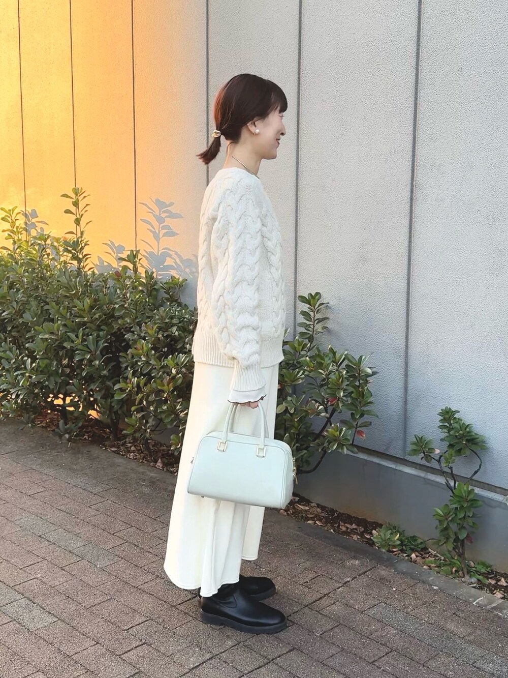 ホワイト系のニット/セーター、ホワイト系のTシャツ/カットソー、グリーン系のショルダーバッグを着用したレディースの冬コーディネートの4枚目の写真