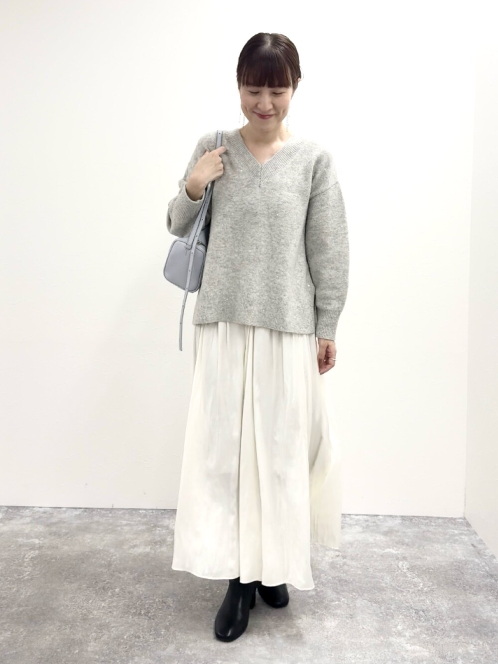 グレー系のニット/セーター、ブルー系のショルダーバッグ、ホワイト系のスカートを着用したレディースの冬コーディネートの8枚目の写真