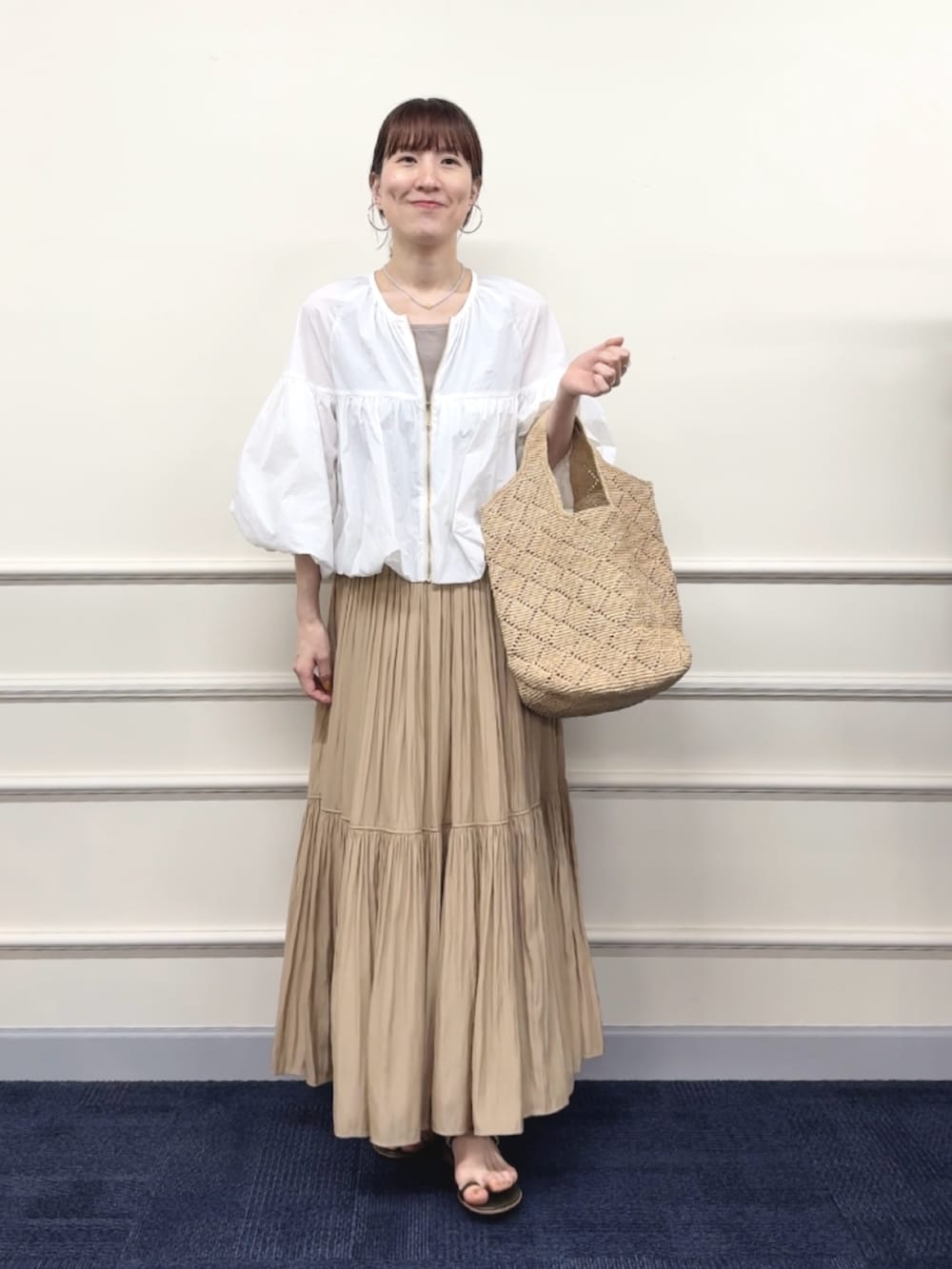 ベージュ系のスカート、ベージュ系のタンクトップ、ホワイト系のブルゾンを着用したレディースの春コーディネートの5枚目の写真