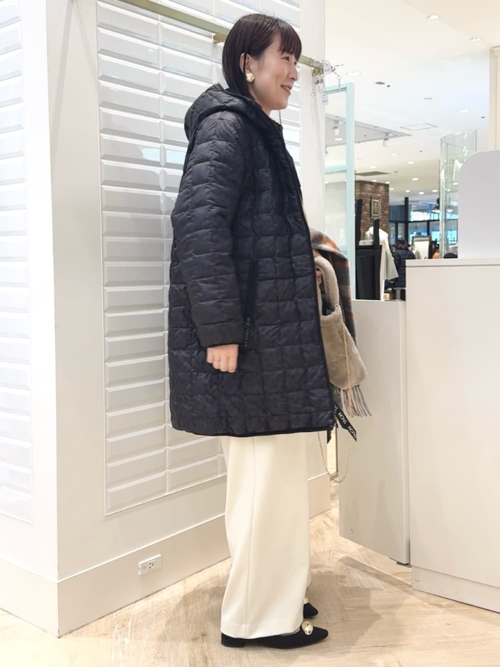 ホワイト系のその他パンツ、ベージュ系のトートバッグ、ブラック系のダウンジャケット/コートを着用したレディースの秋コーディネートの4枚目の写真