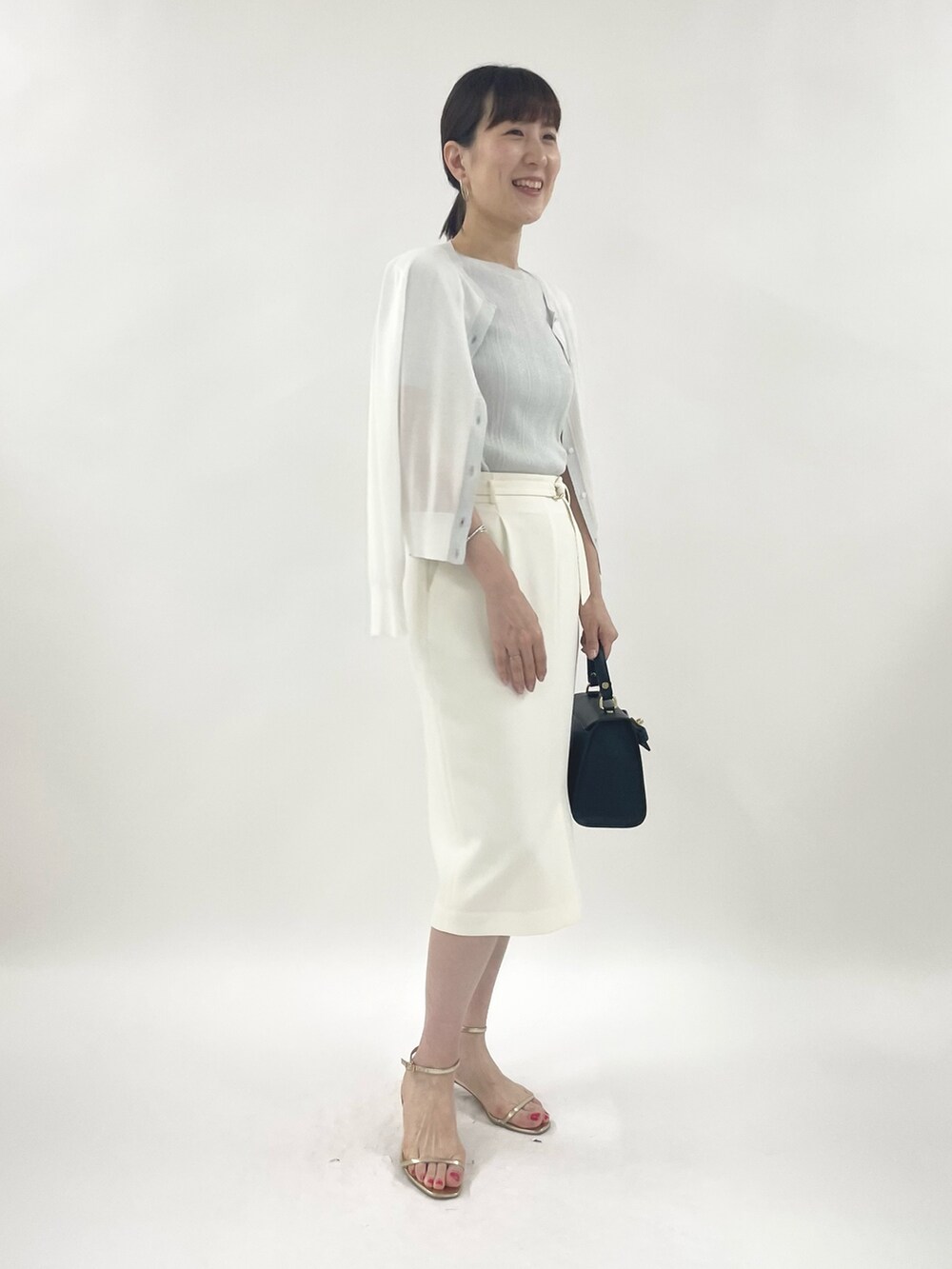 ゴールド系のサンダル、ブラック系のショルダーバッグ、シルバー系のニット/セーターを着用したレディースの春コーディネートの3枚目の写真