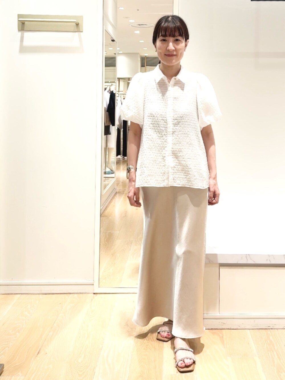 ベージュ系のスカート、ホワイト系のシャツ/ブラウス、ゴールド系のバレッタ/ヘアクリップを着用したレディースの夏コーディネートの2枚目の写真