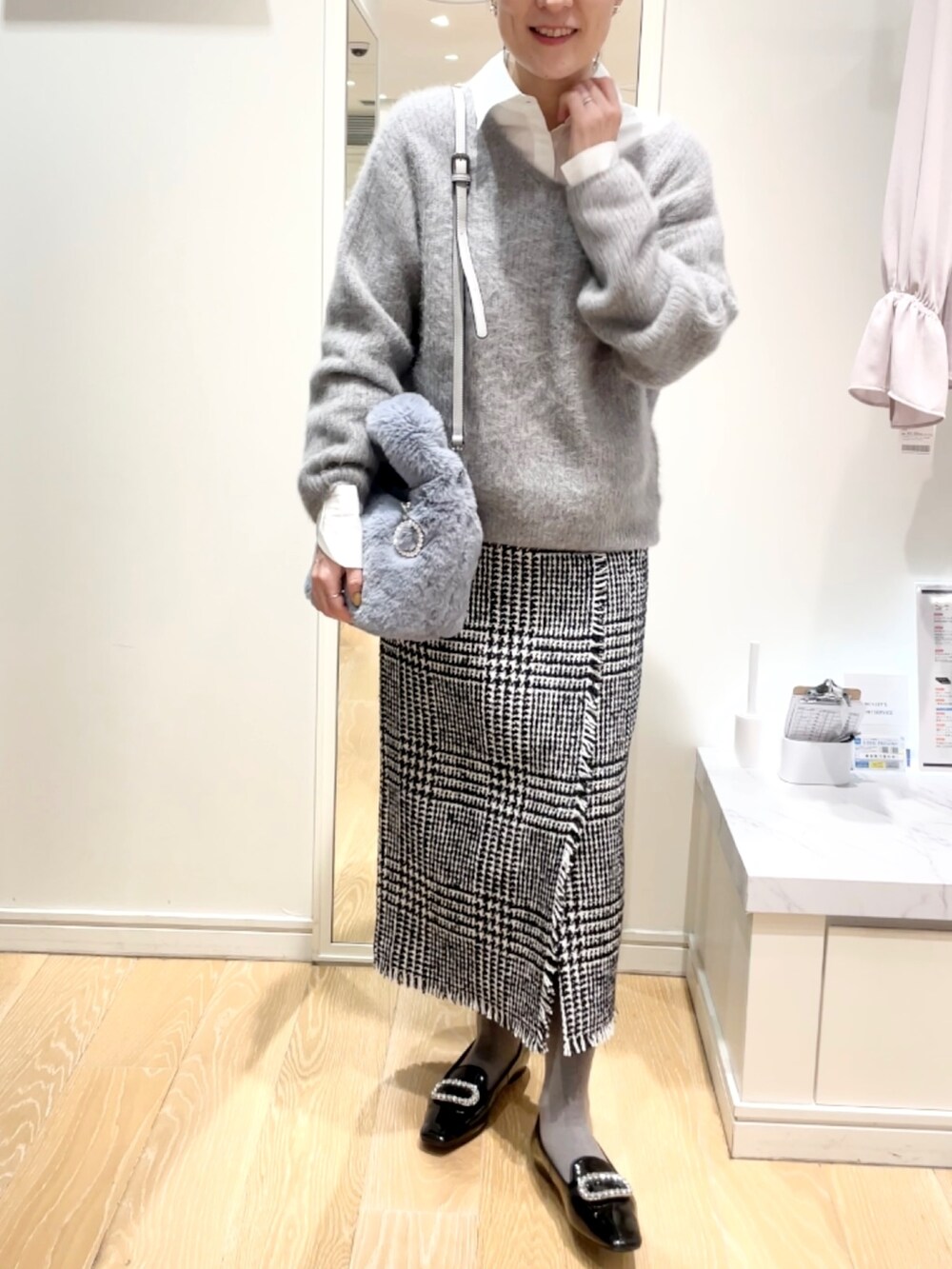 ブラック系のスカート、グレー系のニット/セーター、ブルー系のトートバッグを着用したレディースの冬コーディネートの9枚目の写真