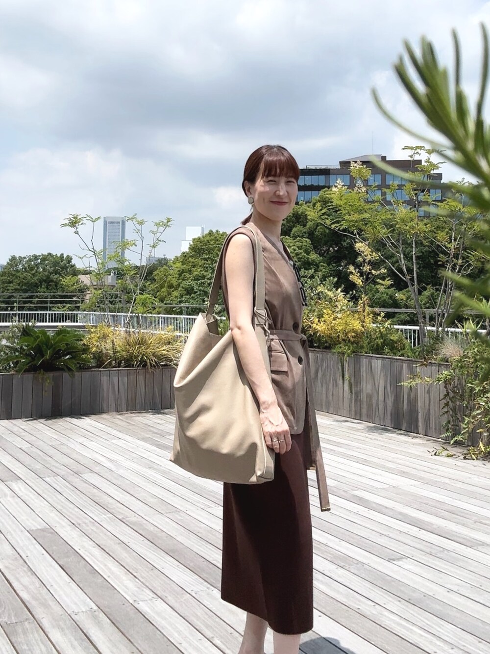 ゴールド系のタンクトップ、ベージュ系のベスト、ベージュ系のショルダーバッグを着用したレディースの秋コーディネートの5枚目の写真