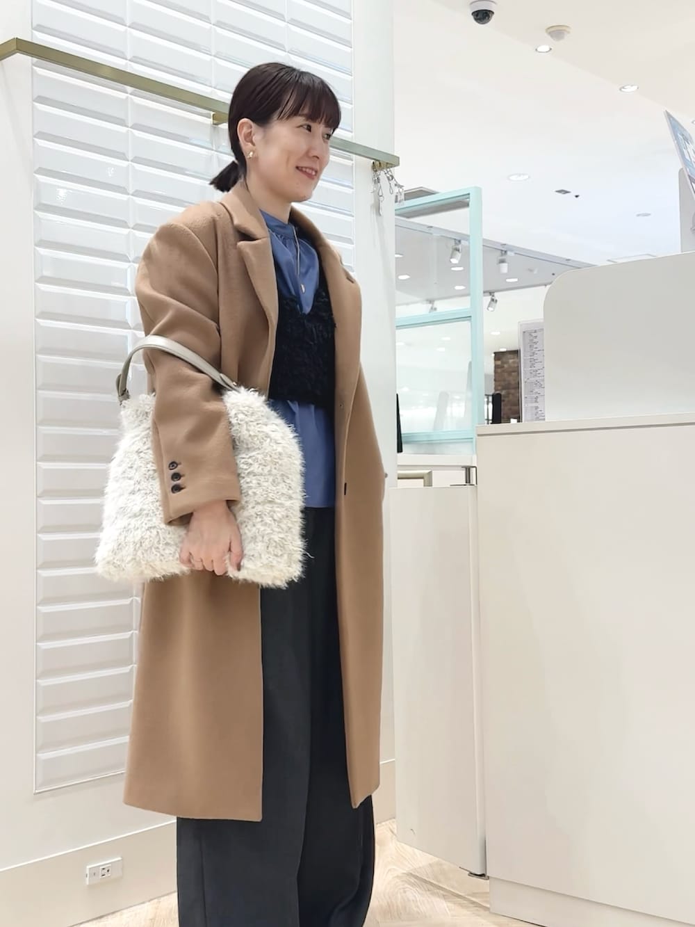 グレー系のベスト、ブルー系のシャツ/ブラウス、ホワイト系のショルダーバッグを着用したレディースの秋コーディネートの3枚目の写真