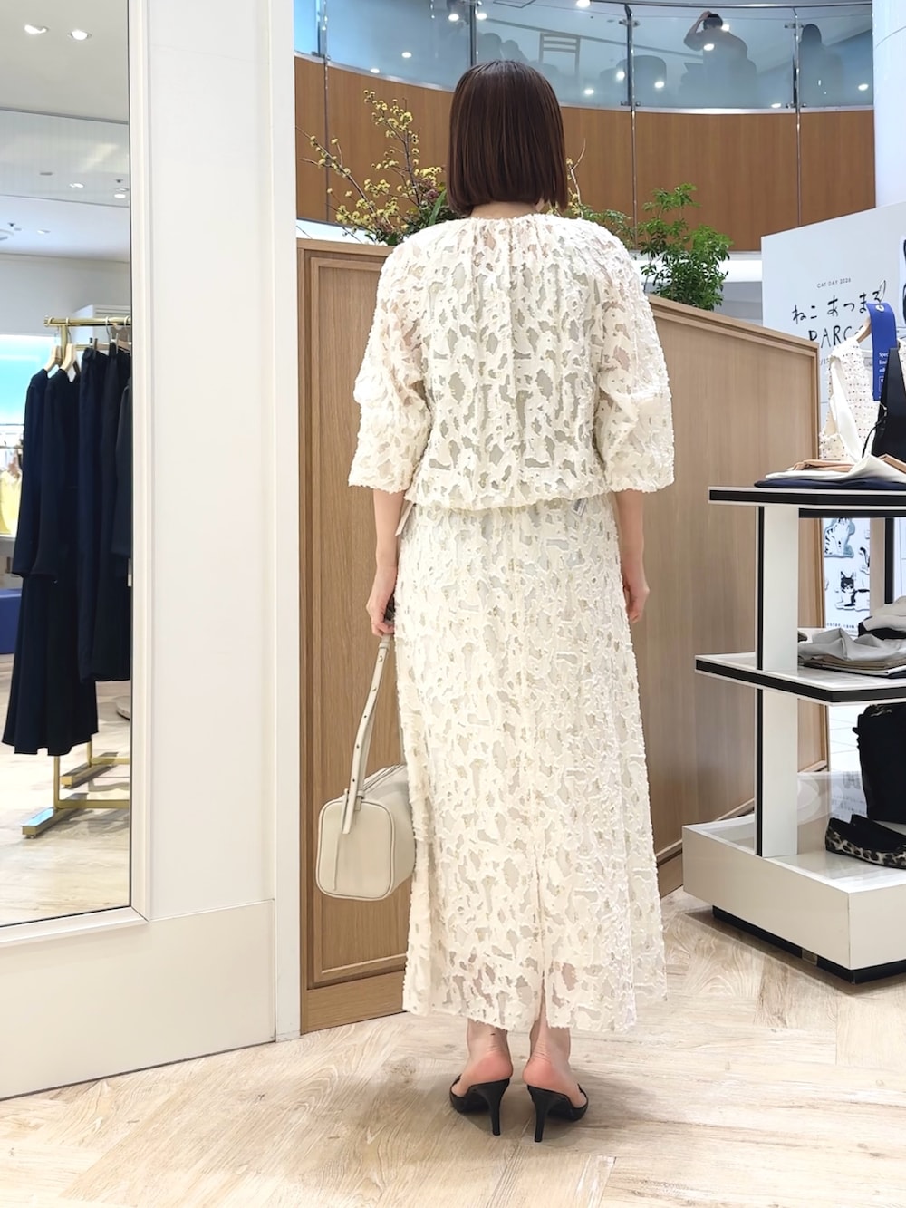 ホワイト系のショルダーバッグ、ゴールド系のタンクトップ、ホワイト系のブルゾンを着用したレディースの冬コーディネートの6枚目の写真