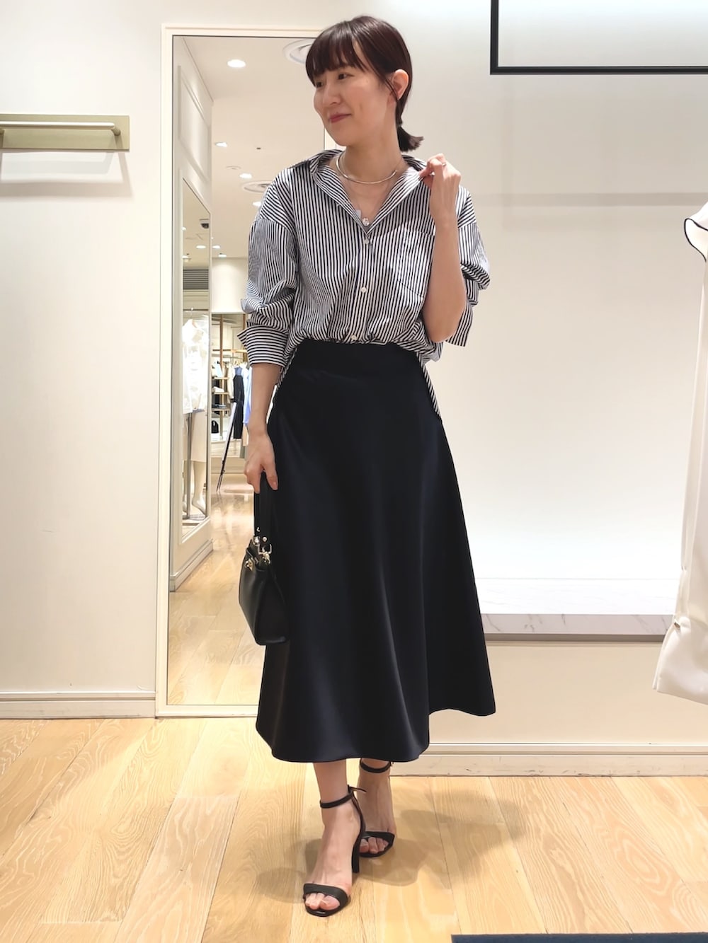 ホワイト系のシャツ/ブラウス、ブルー系のスカート、ブラック系のショルダーバッグを着用したレディースの春コーディネートの2枚目の写真