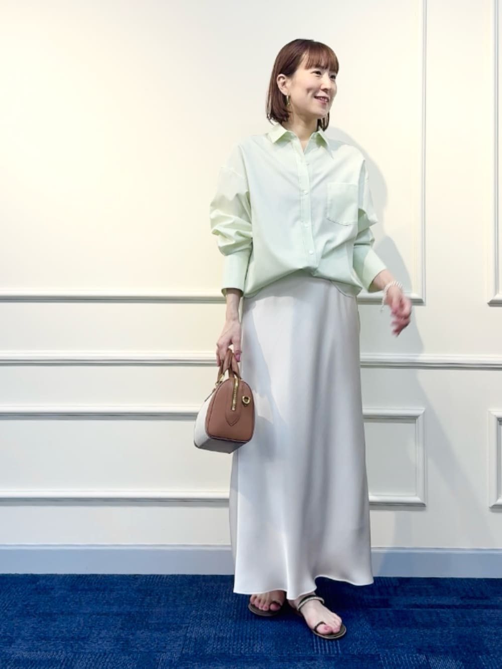 ブラウン系のボストンバッグ、ホワイト系のスカート、グリーン系のシャツ/ブラウスを着用したレディースの冬コーディネートの2枚目の写真