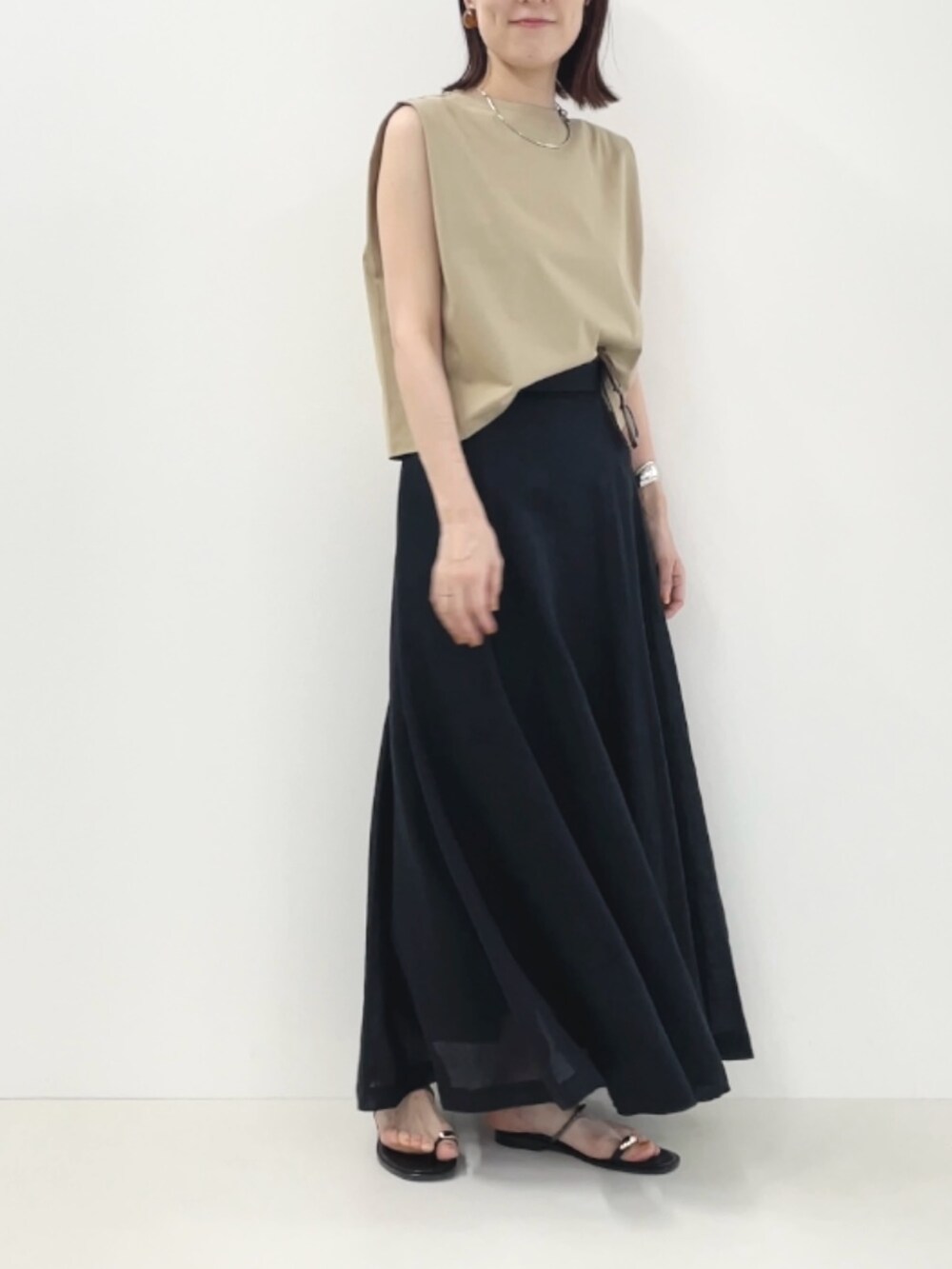 ブラック系のサンダル、ベージュ系のTシャツ/カットソー、ブラック系のスカートを着用したレディースの夏コーディネートの5枚目の写真