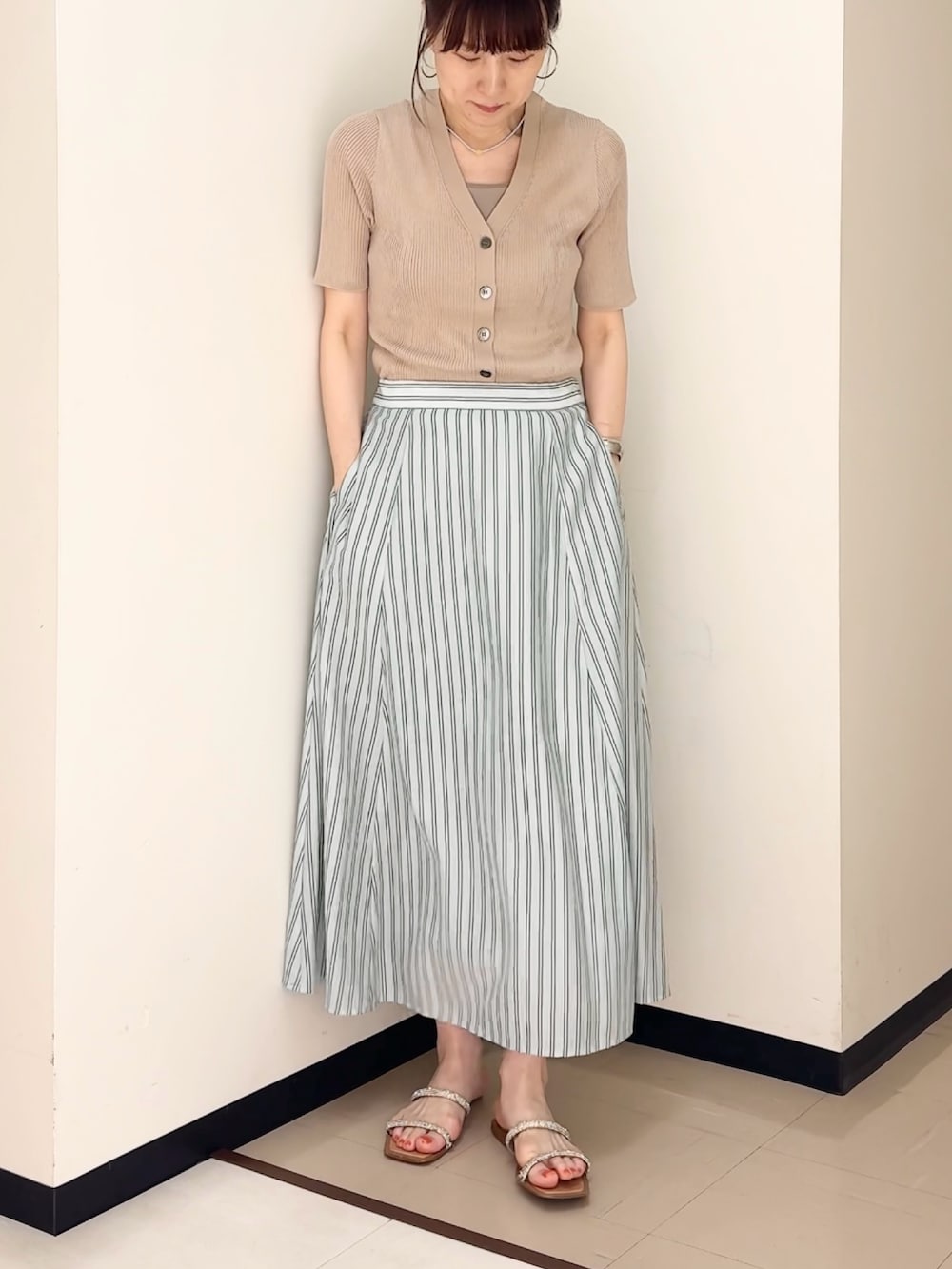 ブルー系のスカート、ベージュ系のカーディガン/ボレロ、ベージュ系のタンクトップを着用したレディースの夏コーディネートの3枚目の写真