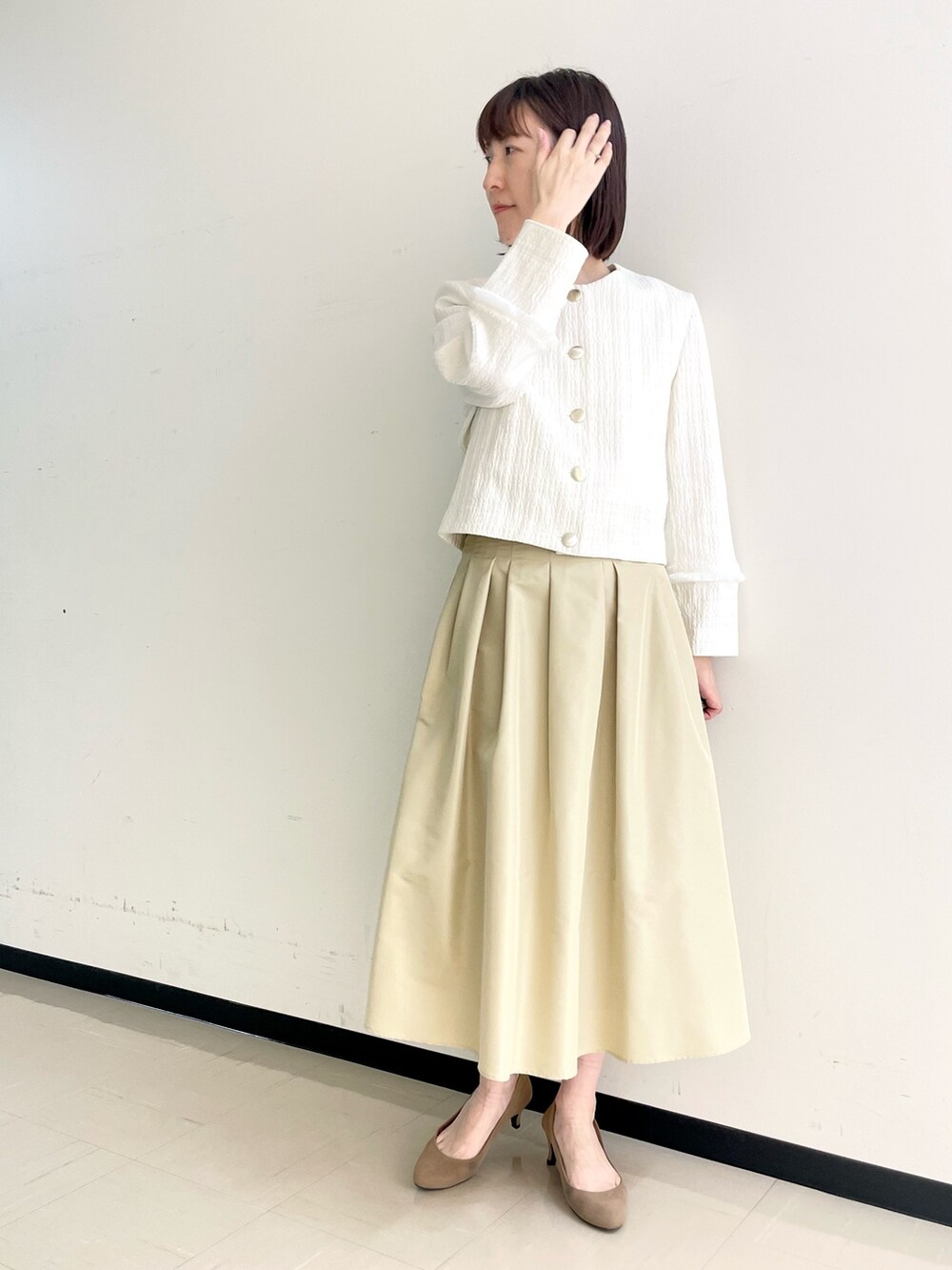 ベージュ系のスカート、ホワイト系のノーカラージャケット、ホワイト系のニット/セーターを着用したレディースの春コーディネートの7枚目の写真