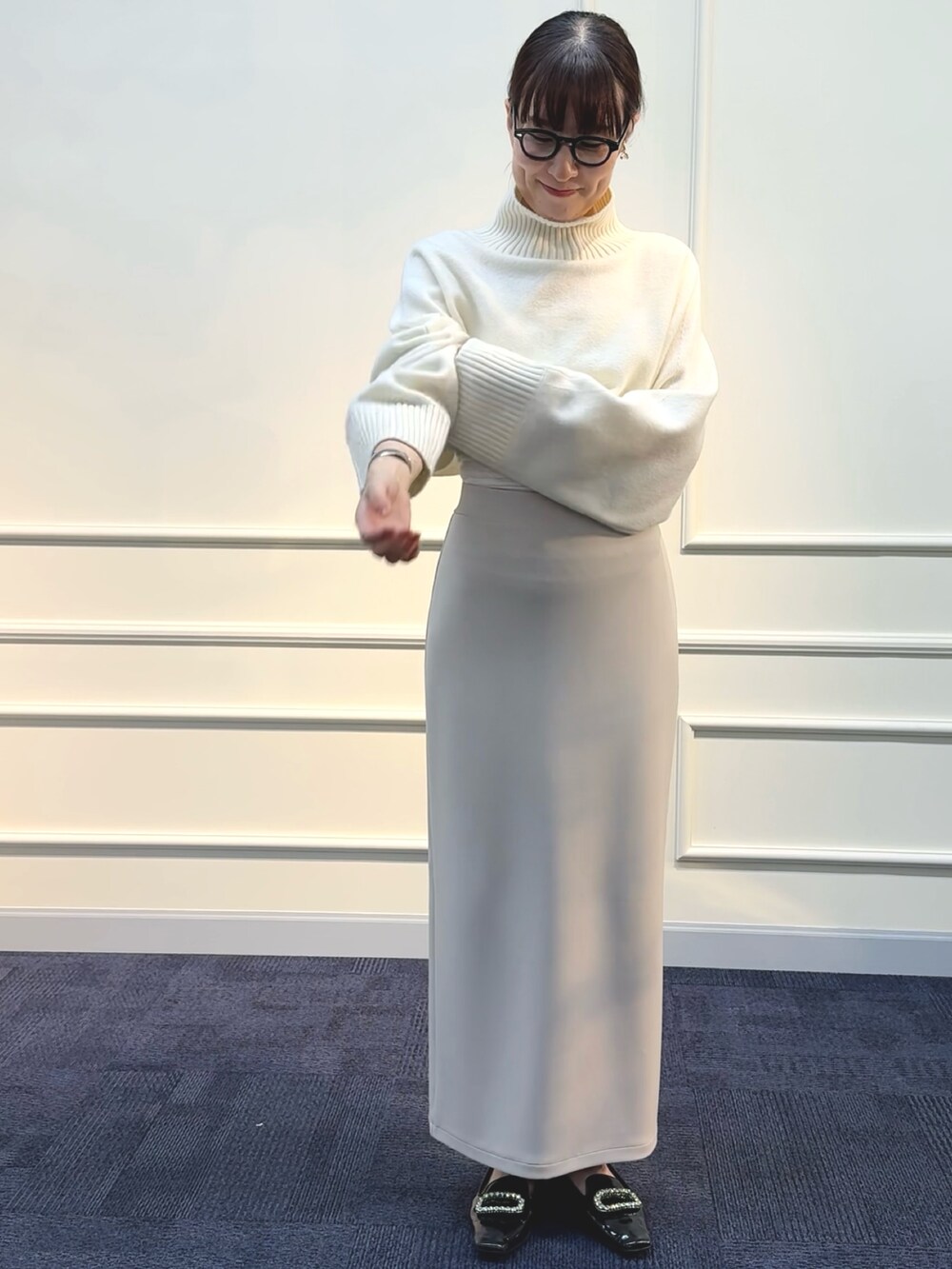 ベージュ系のスカート、ホワイト系のニット/セーターを着用したレディースの秋コーディネートの2枚目の写真