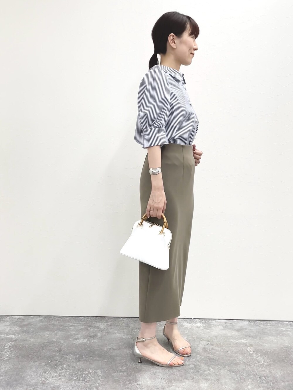 シルバー系のサンダル、グリーン系のスカート、ホワイト系のショルダーバッグを着用したレディースの春コーディネートの5枚目の写真