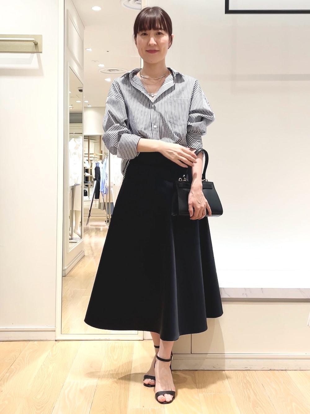 ホワイト系のシャツ/ブラウス、ブルー系のスカート、ブラック系のショルダーバッグを着用したレディースの春コーディネートの5枚目の写真