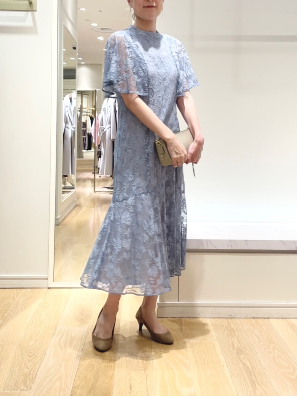 ベージュ系のショルダーバッグ、ブルー系のワンピース、ゴールド系のイヤリングを着用したレディースの秋コーディネートの4枚目の写真