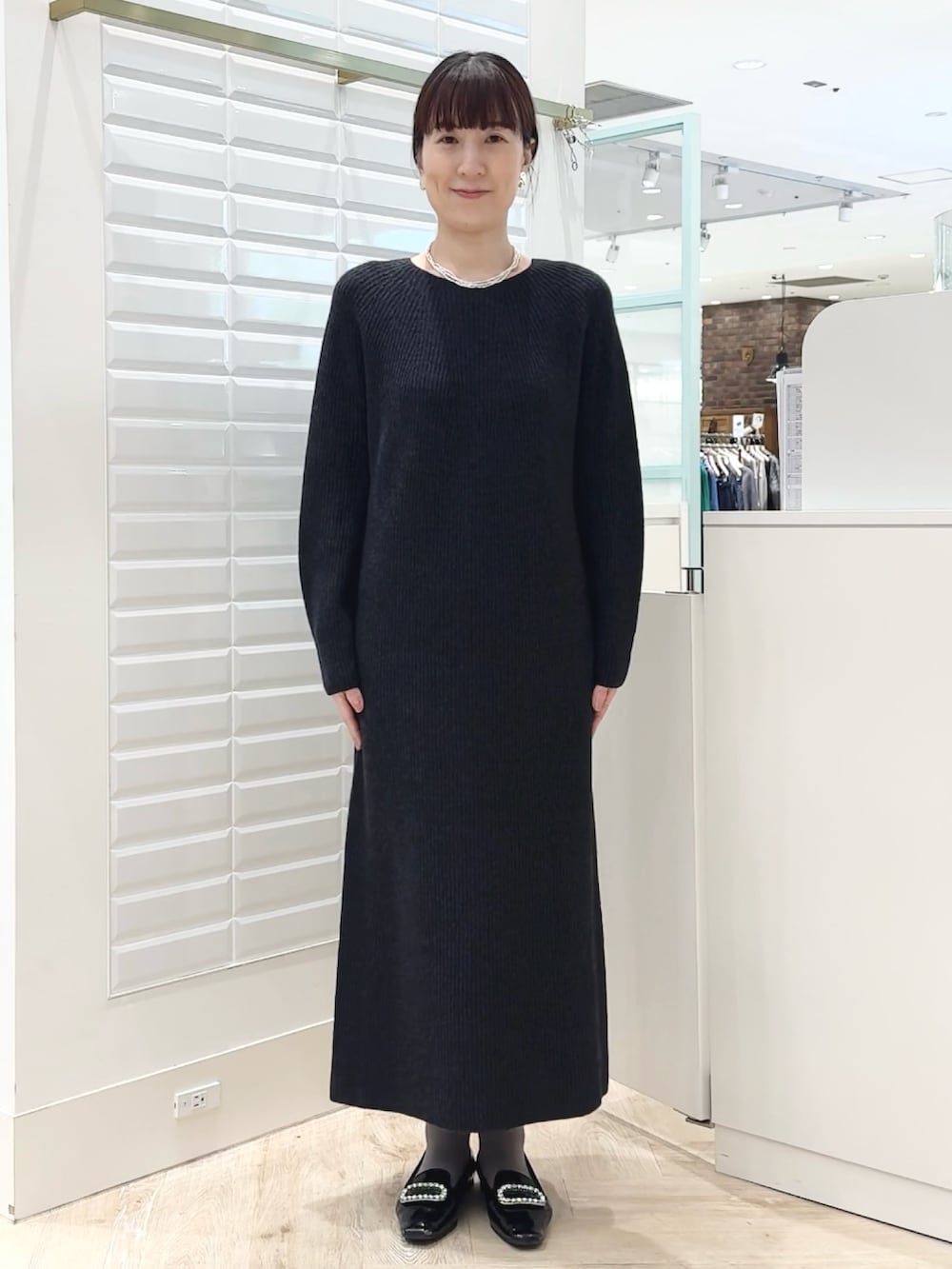 グレー系のワンピース、ゴールド系のイヤリング、ホワイト系のネックレスを着用したレディースの冬コーディネートの8枚目の写真