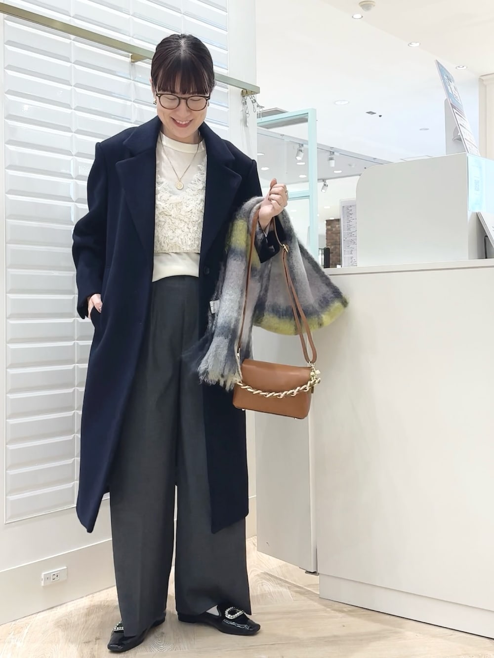 グレー系のその他パンツ、ブルー系のチェスターコート、ホワイト系のベストを着用したレディースの秋コーディネートの6枚目の写真