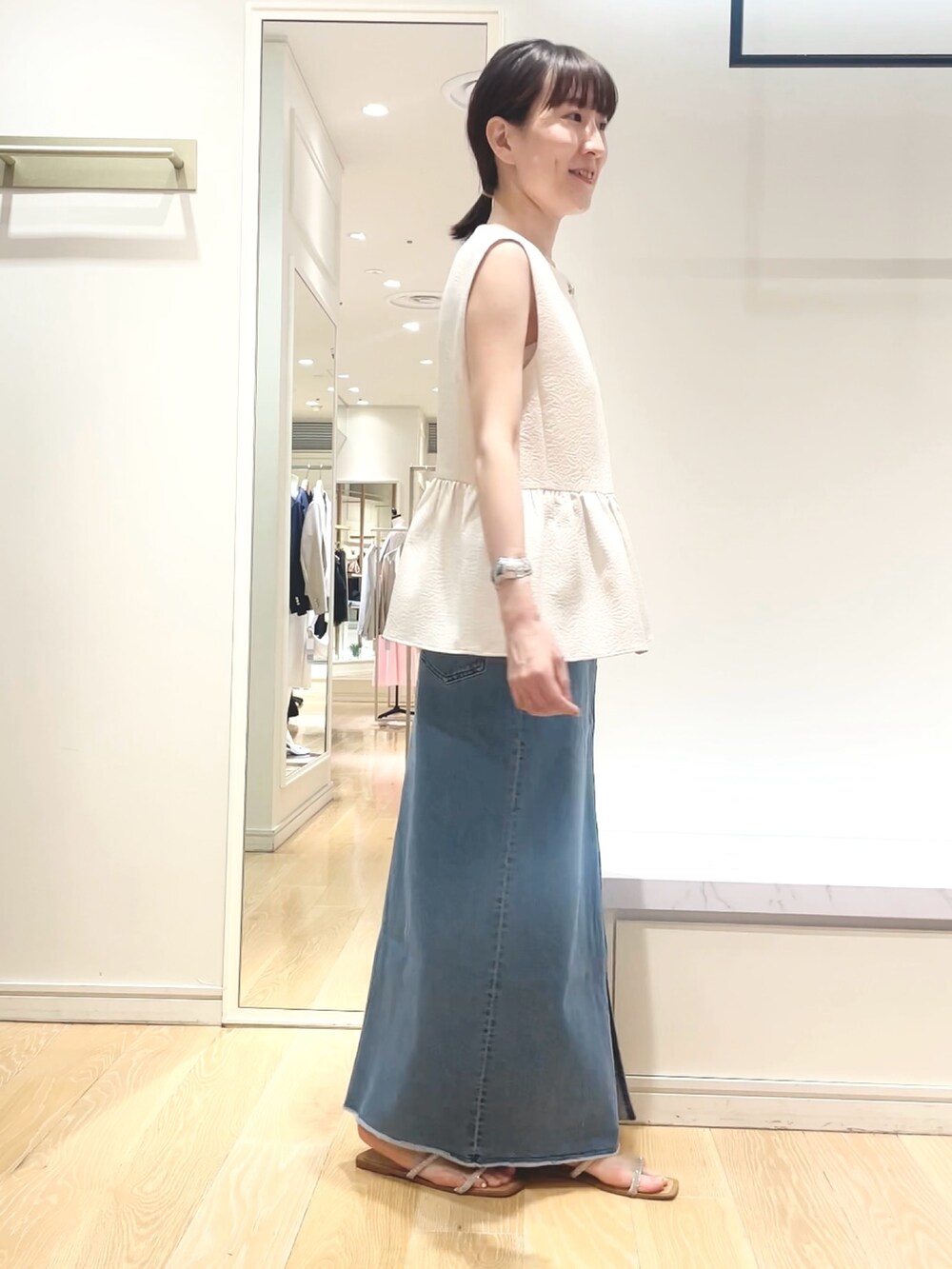 ホワイト系のベスト、グリーン系のショルダーバッグ、ブルー系のデニムスカートを着用したレディースの春コーディネートの10枚目の写真