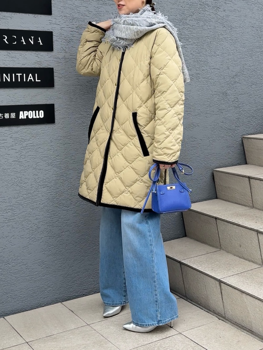 ブルー系のデニムパンツ、ブルー系のショルダーバッグ、ベージュ系のダウンジャケット/コートを着用したレディースの秋コーディネートの5枚目の写真