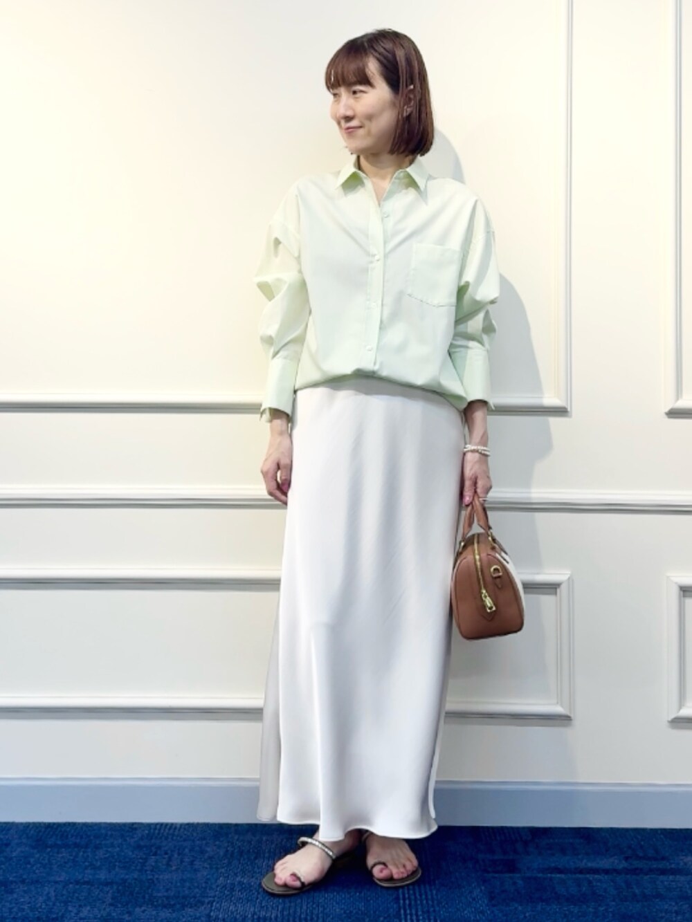 ブラウン系のボストンバッグ、ホワイト系のスカート、グリーン系のシャツ/ブラウスを着用したレディースの冬コーディネートの10枚目の写真