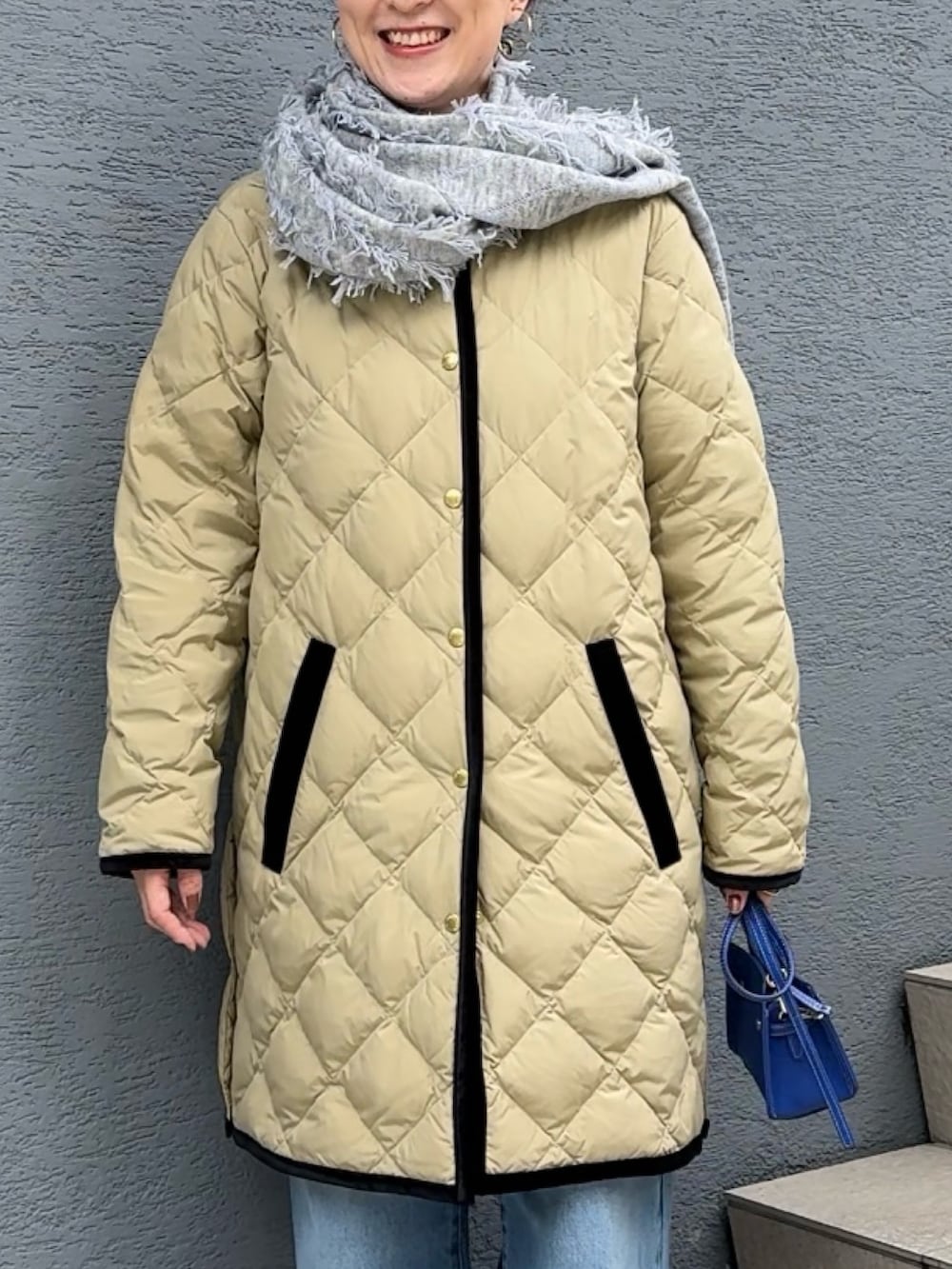 ブルー系のデニムパンツ、ブルー系のショルダーバッグ、ベージュ系のダウンジャケット/コートを着用したレディースの秋コーディネートの7枚目の写真