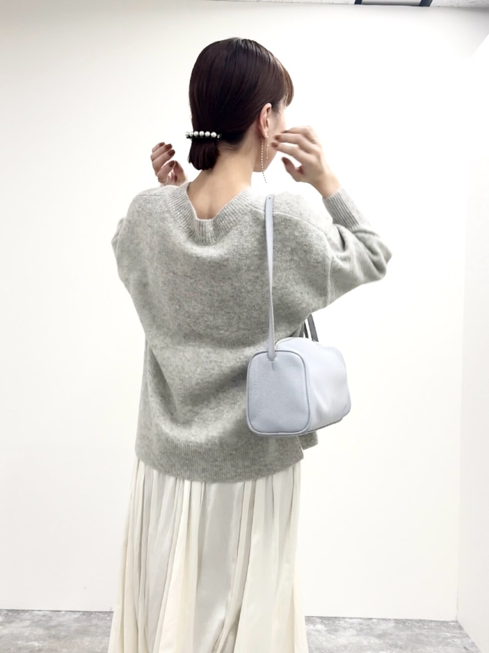 グレー系のニット/セーター、ブルー系のショルダーバッグ、ホワイト系のスカートを着用したレディースの冬コーディネートの9枚目の写真