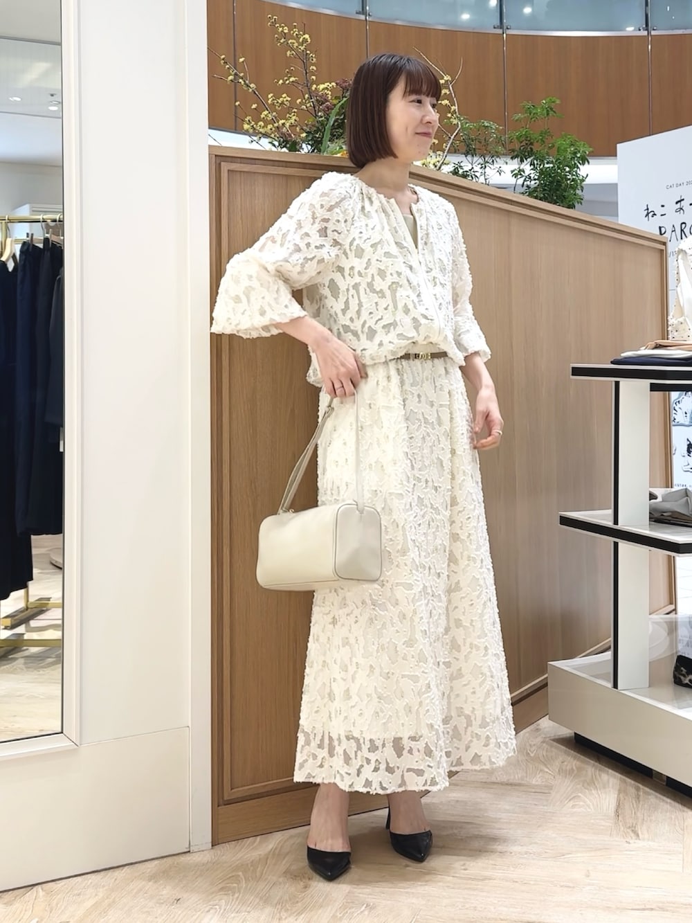 ホワイト系のショルダーバッグ、ゴールド系のタンクトップ、ホワイト系のブルゾンを着用したレディースの冬コーディネートの5枚目の写真