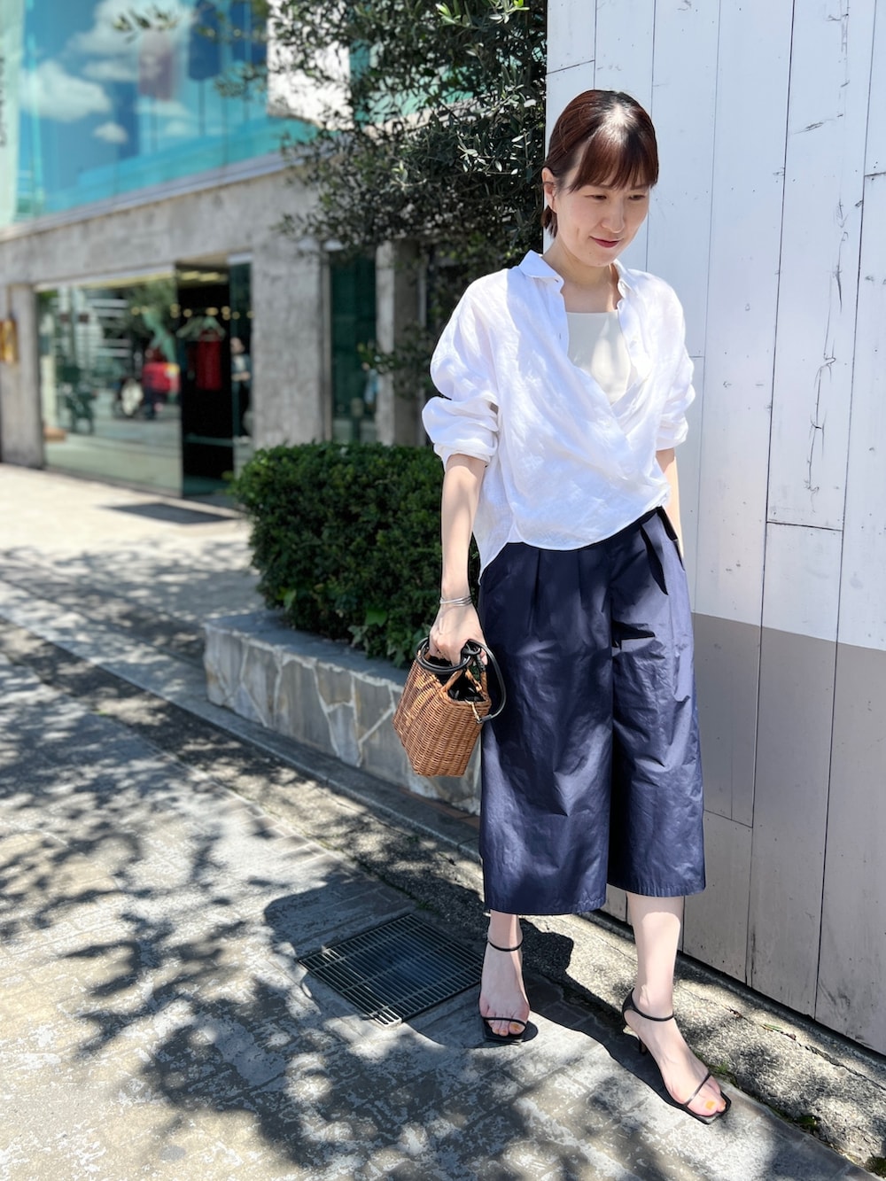 イエロー系のかごバッグ、ブルー系のその他パンツ、ホワイト系のシャツ/ブラウスを着用したレディースの夏コーディネートの4枚目の写真
