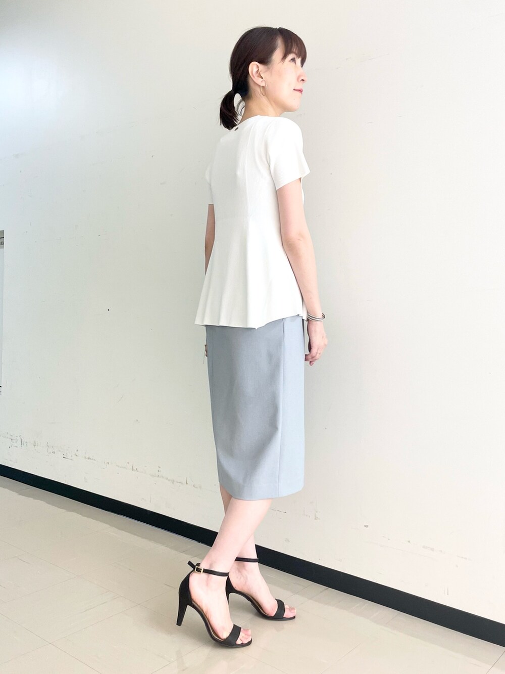 ブルー系のスカート、ホワイト系のニット/セーターを着用したレディースの春コーディネートの3枚目の写真
