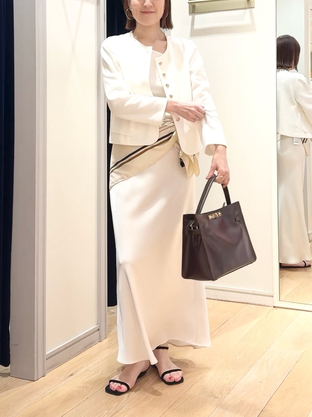 ホワイト系のタンクトップ、ホワイト系のノーカラージャケット、ホワイト系のスカートを着用したレディースの春コーディネートの5枚目の写真