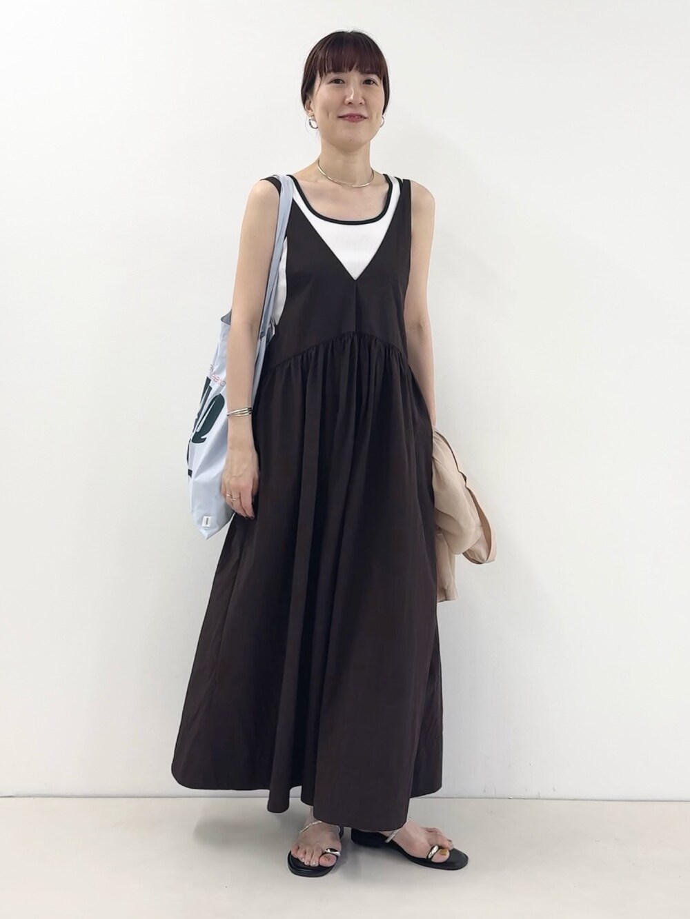 ブルー系のトートバッグ、シルバー系のサンダル、ブラウン系のワンピースを着用したレディースの夏コーディネートの3枚目の写真