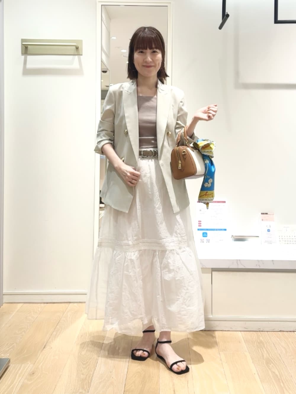 ベージュ系のテーラードジャケット、ベージュ系のタンクトップ、ブラウン系のボストンバッグを着用したレディースの春コーディネートの3枚目の写真